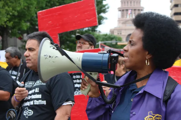 TSEU member speaks into a microphone in front of the Texas Capitol.